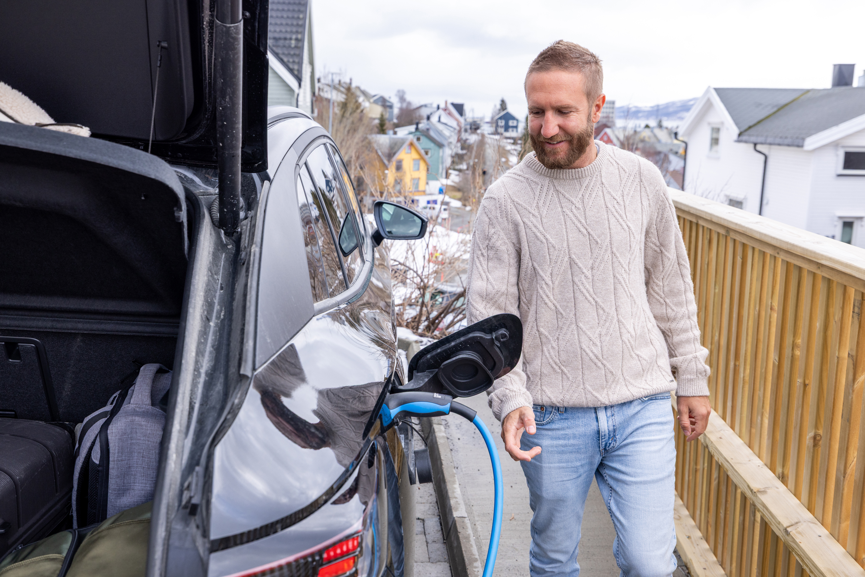 A man charges an electric car at a charging station in Norway.