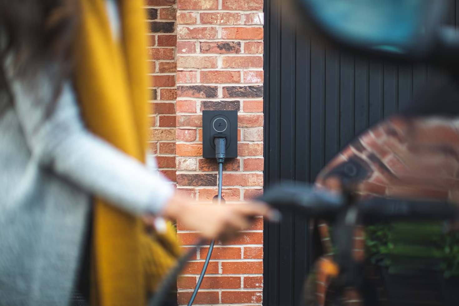 A person plugging a charger into an electric vehicle
