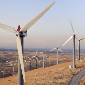High-angle view of a worker atop a wind turbine in a rural setting.