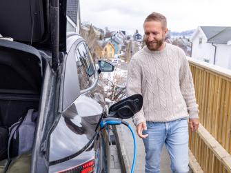 A man charges an electric car at a charging station in Norway.